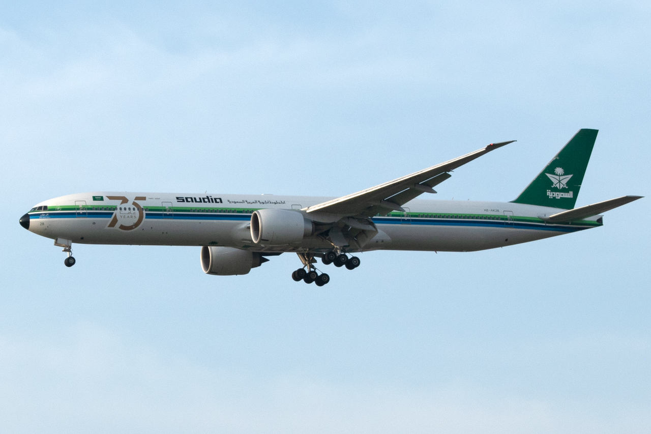 Saudia Airlines aircraft with landing gear extended in flight over Indonesia.