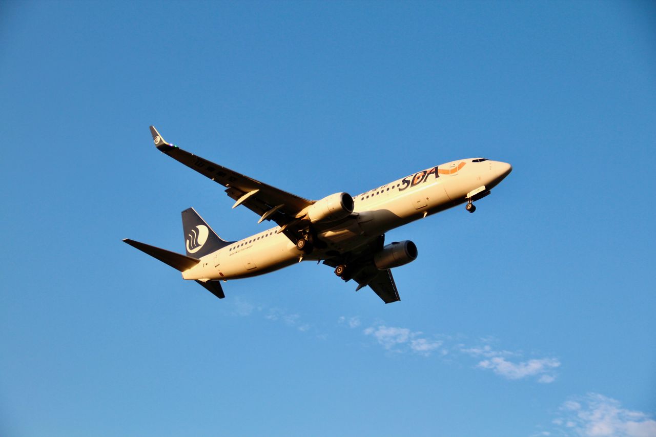 A commercial airplane captured in flight against a clear blue sky, showcasing aviation and travel.
